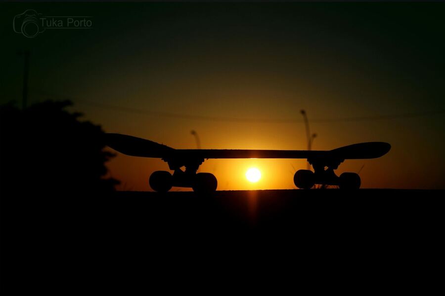 Silhueta do skate contra o sol poente