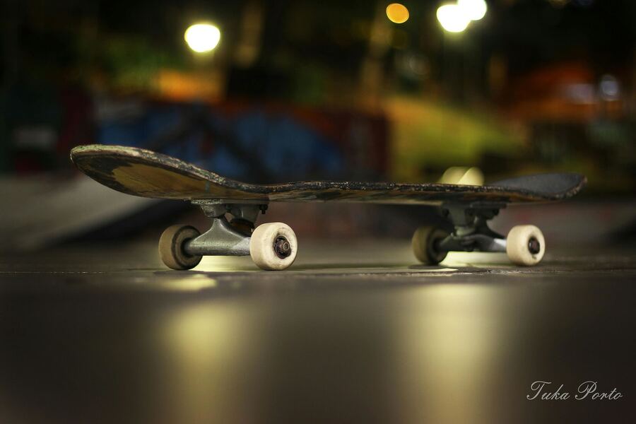 Close no skate, com as luzes da noite ao fundo